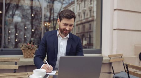 cheerful-businessman-working-at-laptop-in-cafeteri-2022-05-26-05-15-42-utc